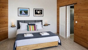 Une chambre à coucher avec un lit, deux tableaux encadrés, des tables de chevet avec des bougies et un mur en bois.