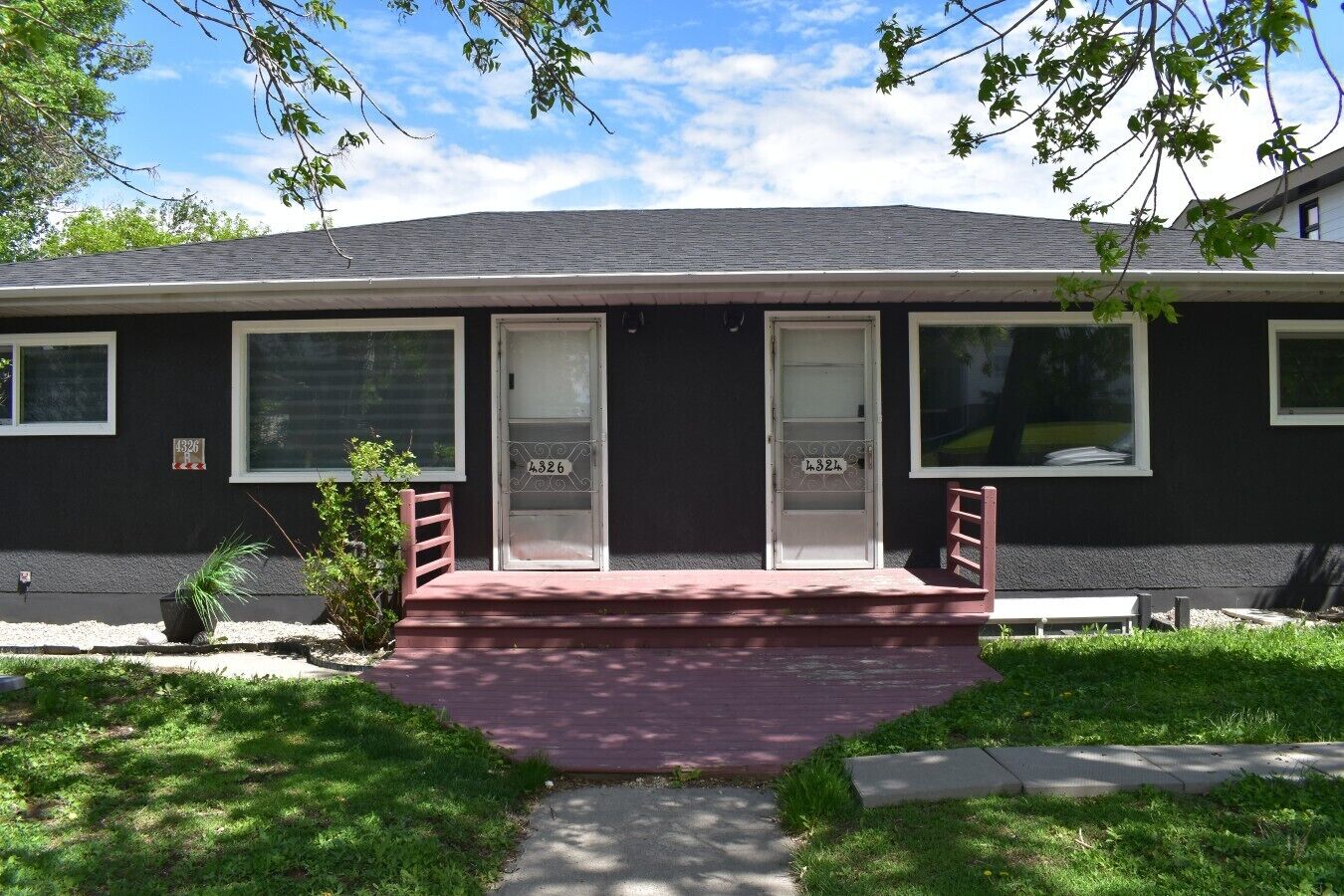 A single-story building with a dark exterior, three doors, and a small porch with steps.
