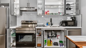 Una cocina moderna con electrodomésticos integrados, estanterías abiertas y una encimera con cafetera.