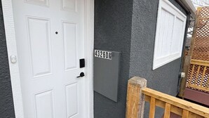 Una puerta blanca con un buzón y una terraza de madera.
