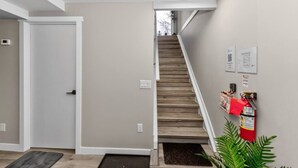 Una escalera que lleva a una plataforma con un extintor de incendios montado en la pared.