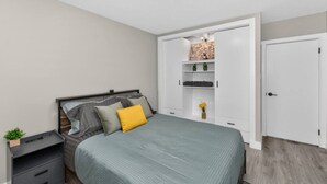Een slaapkamer met een bed, nachtkastjes, een kledingkast en een kleine plant.