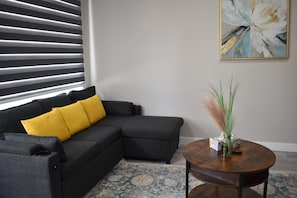 A modern living room with a sectional sofa, a round coffee table, and a decorative vase.