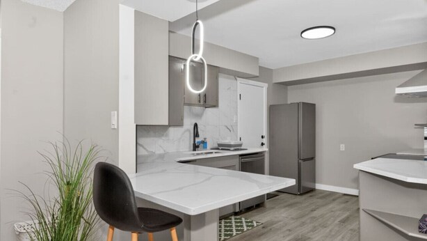 Una cocina moderna con una isla central, un comedor con una silla y una planta en maceta.