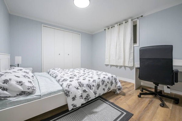 Bright bedroom with comfortable bed and workspace setup.