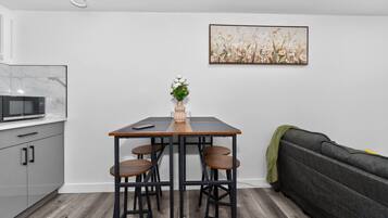 Een kleine keuken met een magnetron, een eettafel met krukken, en een bank.