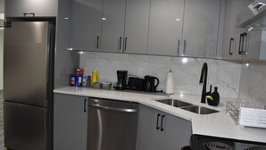 A modern kitchen with stainless steel appliances, grey cabinets, and a marble backsplash. - Modern 2BR Basement Suite Near Downtown & Airport, SAIT, UofC | Ideal for Business Travel & Stampede Stays (Calgary)