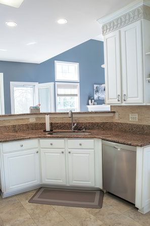 A kitchen with white cabinets, a granite countertop, a stainless steel dishwasher, and a brown mat. - South CLT Getaway - Near Carowinds, I485, I77, Lake Wylie - Firepit (Charlotte)