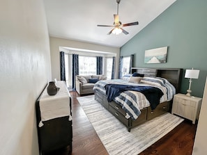 A bedroom with a bed, a desk, a chair, a nightstand, a lamp, a ceiling fan, and a window with curtains. - South CLT Getaway - Near Carowinds, I485, I77, Lake Wylie - Firepit (Charlotte)