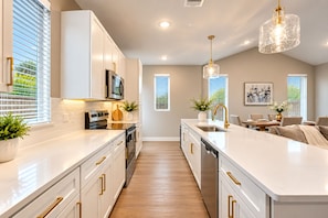A modern kitchen with white cabinetry, stainless steel appliances, and a central island. - THE ELITE ESCAPE Modern luxury with Cozy Comfort (Frisco)