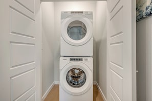 A laundry room with two stacked Whirlpool front-loading washing machines. - THE ELITE ESCAPE Modern luxury with Cozy Comfort (Frisco)
