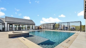 A modern building with a swimming pool and a covered outdoor area. - THE ELITE ESCAPE Modern luxury with Cozy Comfort (Frisco)