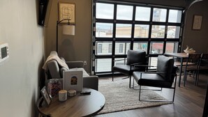 A modern room with a sofa, chairs, a small table, a large window, and a view of buildings outside.