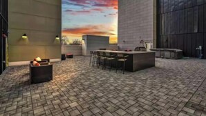 An outdoor patio with a brick floor, a bar area with stools, and a sunset view.