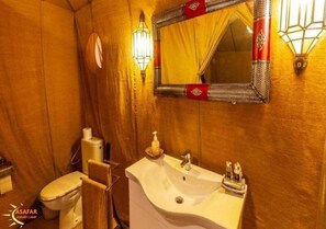 Ein Badezimmer mit Holzwand, einem weißen Waschbecken inklusive Spiegel und einer Toilette.
