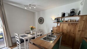 A compact kitchen with a wooden countertop, a sink, and a dining area with chairs and a table. - 239 - Holiday home for 4 people – Domaine des Sables (SOULAC SUR MER)