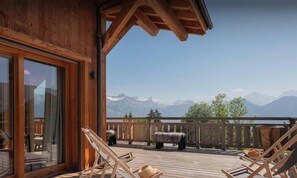 A wooden deck with lounge chairs, a glass door, and a view of snow-capped mountains. - Chalet Condor Andino - Relaxing break near Mont Blanc - OVO Network (Combloux)