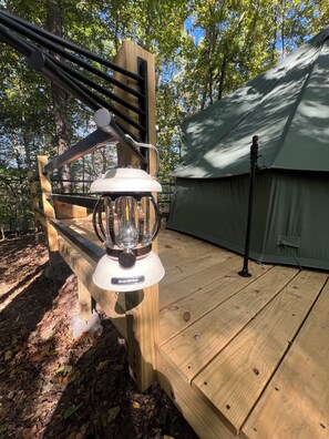 A wooden deck with a white lantern-style light fixture and a tent in the background. - Luxury Camping Retreat just 25 min outside of Nashville (Joelton)
