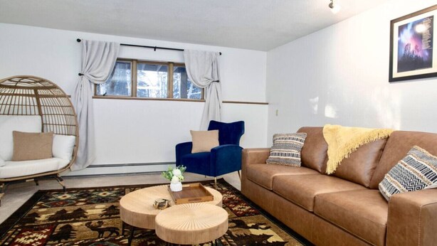 A living room with a sofa, armchair, round coffee table, and patterned rug. - Cozy Bear Den Rustic Cabin Central Located (Fairbanks)