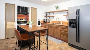 Une cuisine compacte comprenant une table à manger, des chaises, un réfrigérateur et un four à micro-ondes.