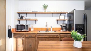 A kitchen with wooden cabinets, a microwave, a coffee maker, and a refrigerator. - Cozy Bear Den Rustic Cabin Central Located (Fairbanks)