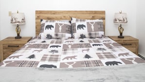 Un lit recouvert d’une couvre-lit à motifs animaliers à carreaux, avec deux oreillers assortis et deux lampes de chevet décorées de motifs animaliers.