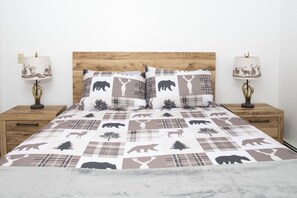 A bed with a checkered animal print bedspread, two matching pillows, and two bedside lamps with animal designs.