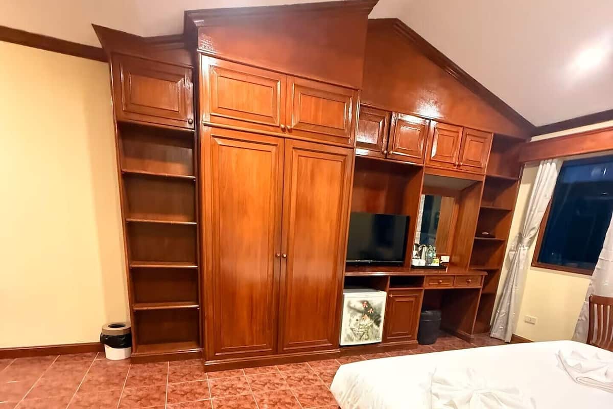 Ein Schlafzimmer mit einem großen Bett, einem Holzschrank und einem Fernseher.