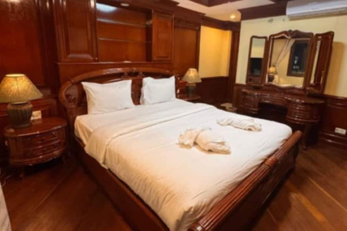Ein großes Bett mit Holzrahmen, weißer Bettwäsche, Holznachtischen und einer Deckenleuchte.