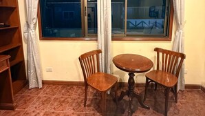 Ein Zimmer mit Esstisch und Stühlen, einem fenster mit Vorhängen und einem gefliesten Boden.