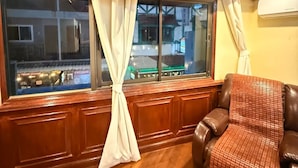 Ein Zimmer mit großem Fenster, Holzvertäfelung, einem Ledersessel und einer Klimaanlage.
