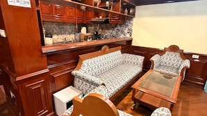 Ein Zimmer mit einer Sitzecke mit Holzbank, einem kleinen Tisch und einem Regal mit Dekorationen.