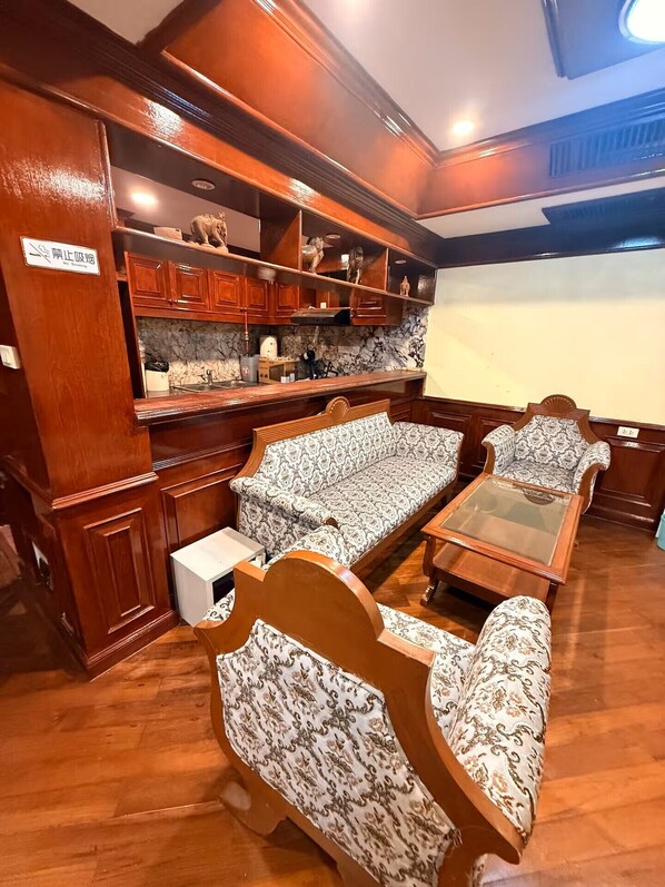 A room with a wooden bench seating area, a small table, and a shelf with decorative items. - Playsales Bliss Casa Boutique Hotel (Patong)
