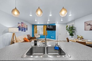 A modern kitchen with a central island, stainless steel sinks, and pendant lighting. - Modern Lux Getaway Heart of Fairbanks (Fairbanks)