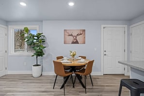 A dining area with a round table, chairs, a potted plant, and a deer antler artwork on the wall. - Modern Lux Getaway Heart of Fairbanks (Fairbanks)