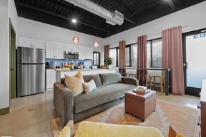A modern kitchen with stainless steel appliances, a grey sofa, and a dining area with a table and chairs. - Modern 1BR Near BNA Airport & Downtown Nashville (Nashville)