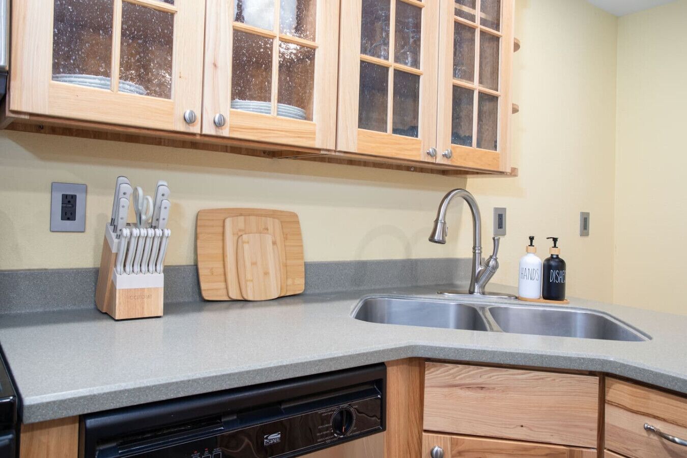 A kitchen with wooden cabinets, a sink, a dishwasher, and a knife block.