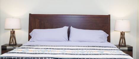 A bed with a patterned bedspread, two bedside lamps, and a wooden headboard.
