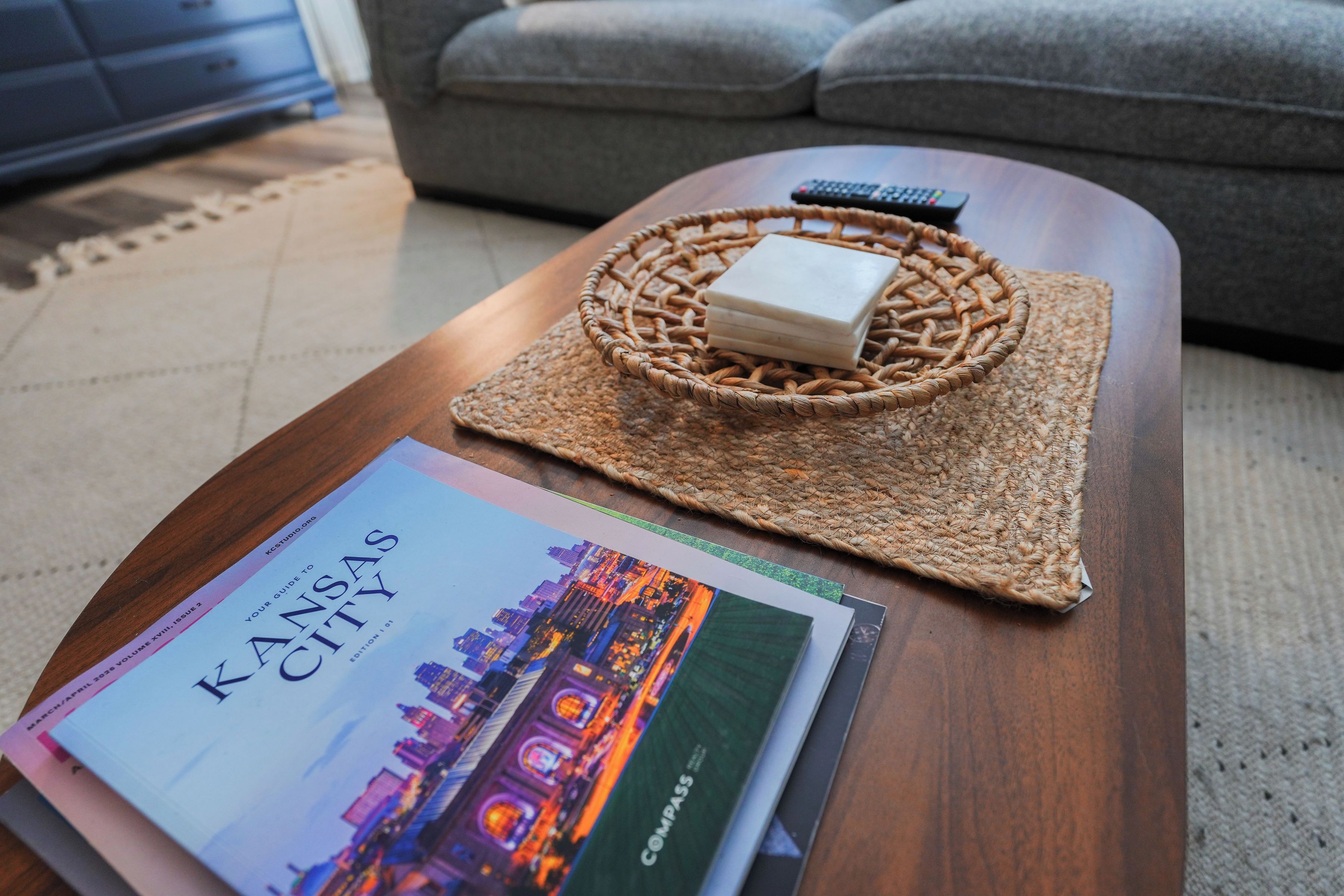 Un livre intitulé « Kansas City » est posé sur une table en bois, accompagné d’une nappe en fibres tressées et d’un savon.
