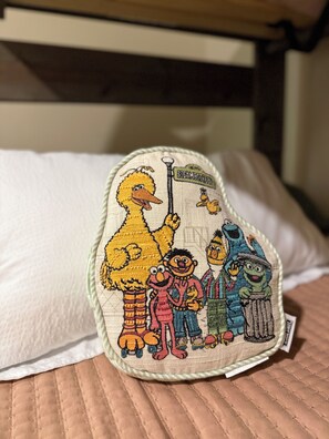 A pillow with embroidered characters from Sesame Street.