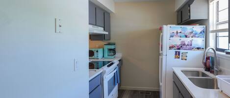 Una cocina compacta con horno integrado, microondas y refrigerador.