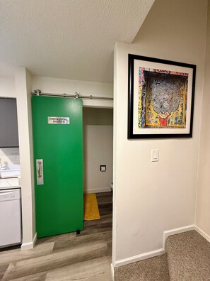 A hallway with a green door labeled 'Operating Room II,' a framed artwork on the wall, and a carpeted floor.