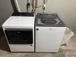 Two Whirlpool appliances, a dryer and a washer, side by side with visible control panels and a power outlet above.
