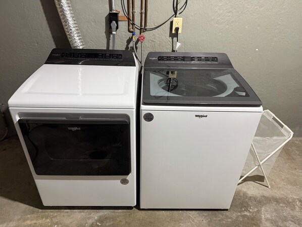 Two Whirlpool appliances, a dryer and a washer, side by side with visible control panels and a power outlet above.