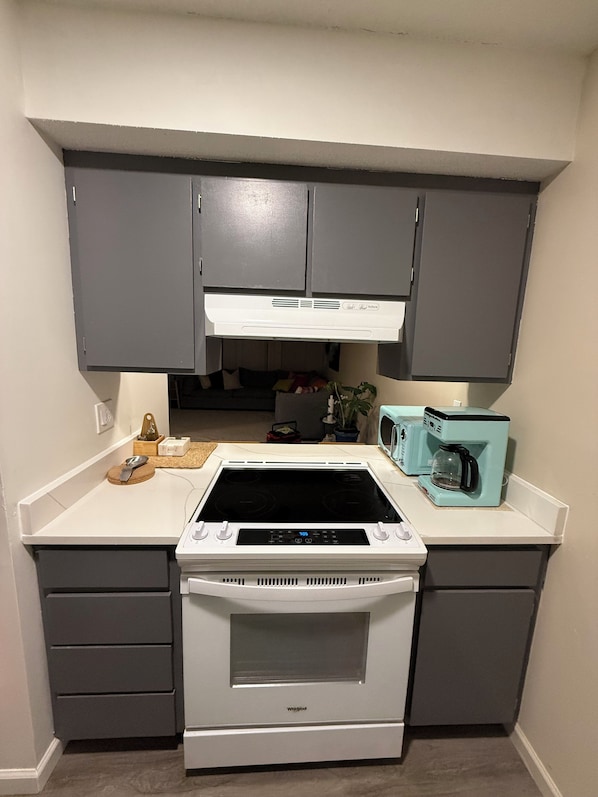 A compact kitchen with a built-in stove, microwave, and a coffee maker on the countertop.