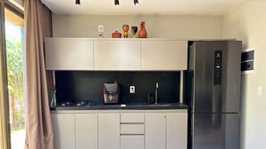 A modern kitchen with a refrigerator, a coffee maker, and a gas stove. - Seaside Studio on the ecological route of Milagres (Porto de Pedras)