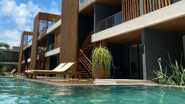 A modern hotel with a pool, wooden balconies, and a clear blue sky. - Seaside Studio on the ecological route of Milagres (Porto de Pedras)