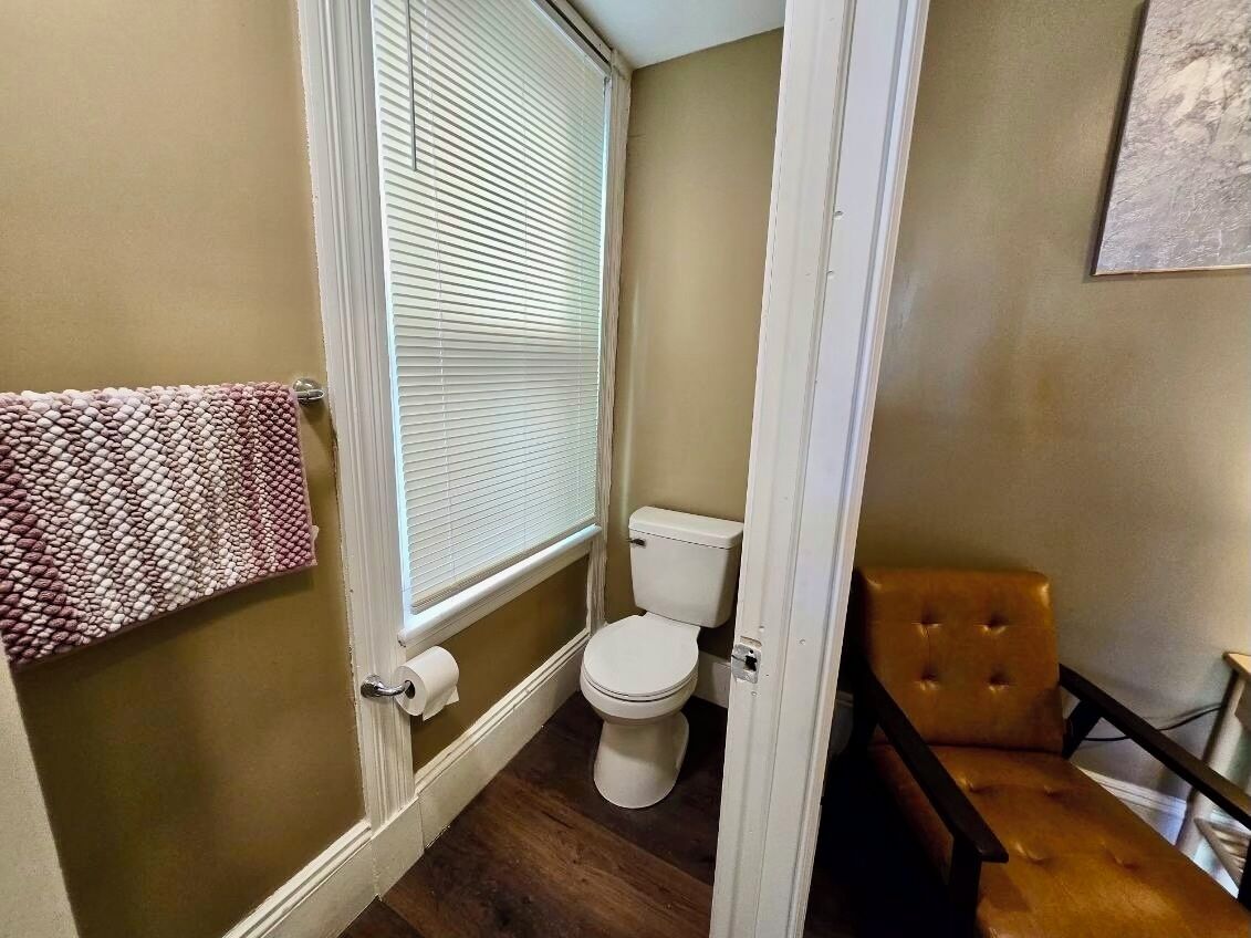 A bathroom with a toilet, a towel rack, and a window with blinds.
