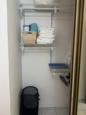 Ein Badezimmer mit Handtuchhalter, einem Korb und Ablagefläche für Toilettenartikel.
