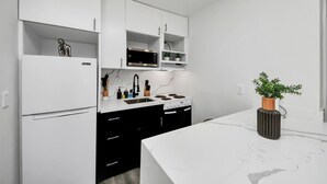 Cozinha moderna com armários brancos, micro-ondas embutido e fogão.
